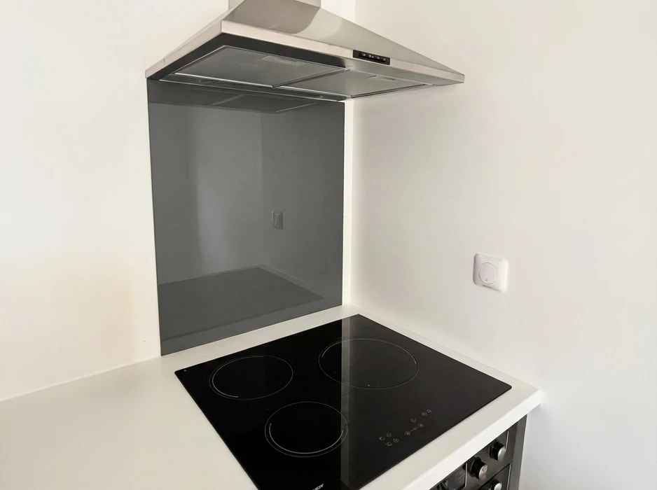 Cuisine moderne minimaliste, plan de travail blanc avec table de cuisson vitrocéramique 4 foyers noire encastrée