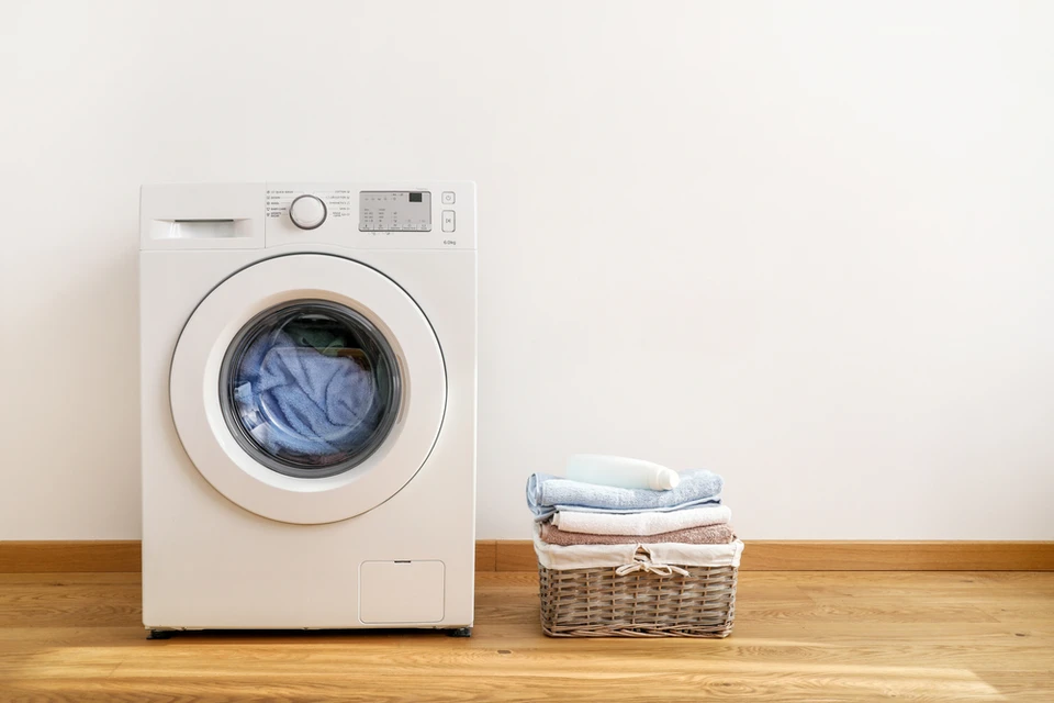 Intérieur domestique avec machine à laver blanche en fonctionnement, linge bleu visible dans le tambour