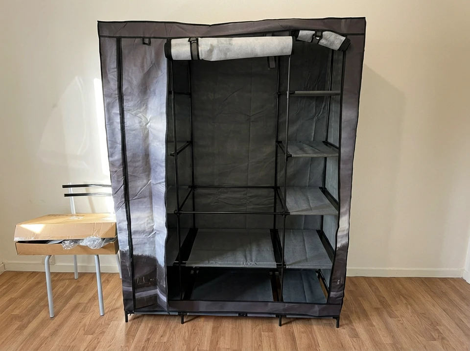 Photographie réaliste montrant un professionnel équipé de ses outils (tournevis, clé, visseuse) en train d'assembler un meuble de cuisine ou une armoire à portes dans un intérieur résidentiel, avec des pièces détachées étalées, du matériel de montage dispersé sur le sol, et une notice d'instruction visible. L'image doit capturer l'expertise et la concentration du professionnel en action, montrant la réalité du travail de montage de meubles kit en domicile client.